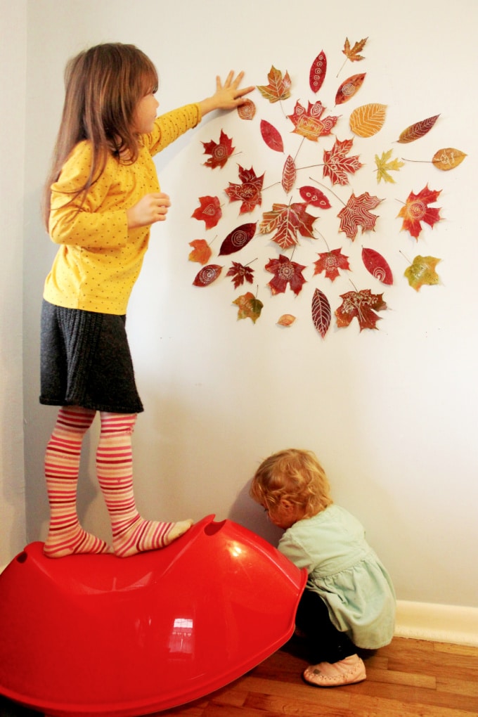 attaching leaves to wall to make a mandala