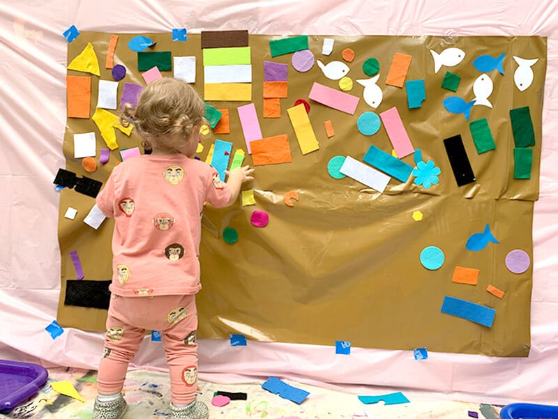 Child-placing-felt-on-contact-paper-wall-for-low-mess-creative-activities.jpg