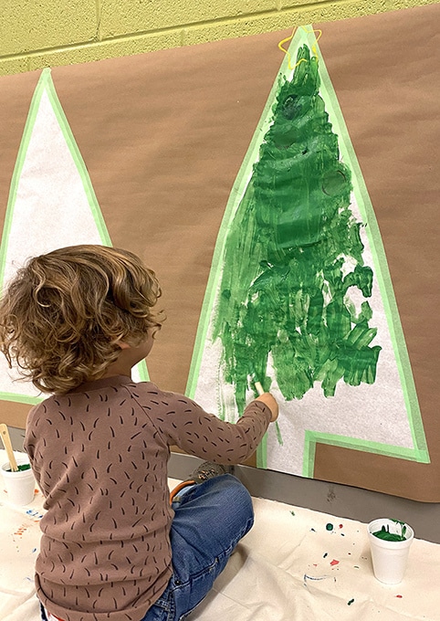 Boy painting Christmas tree on the wall