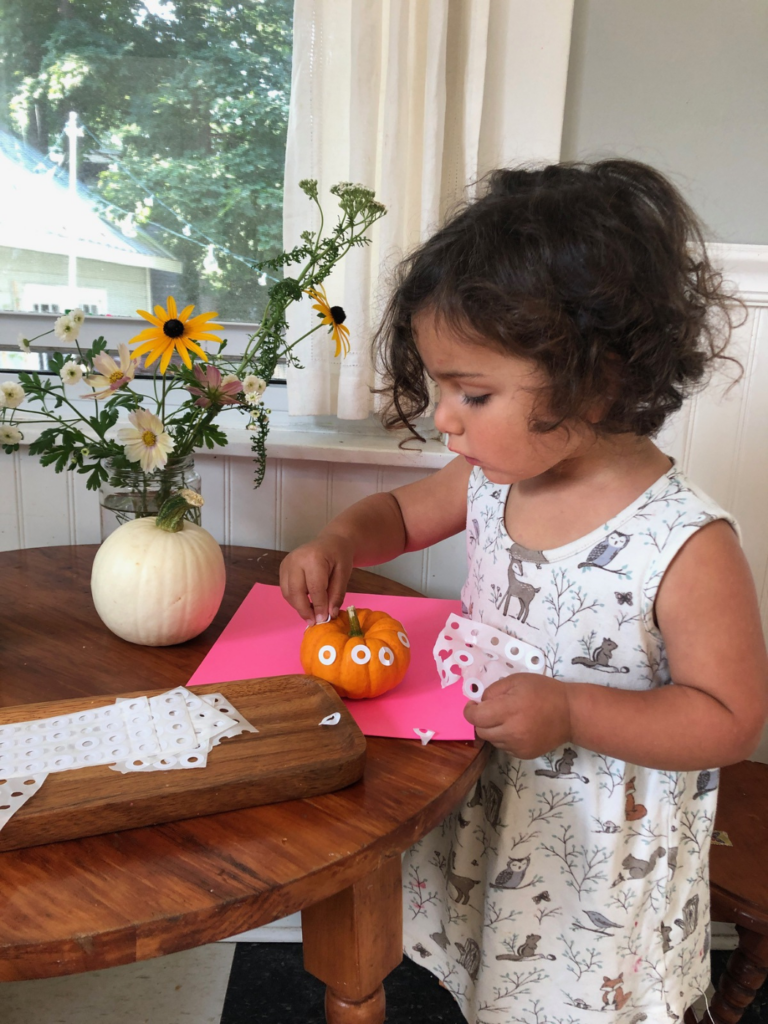 child applying stickers to pumpkin
