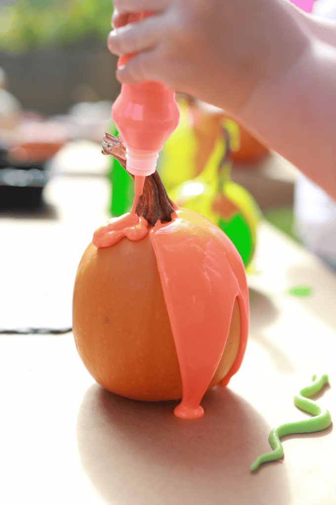 squeezing orange paint onto pumpkin
