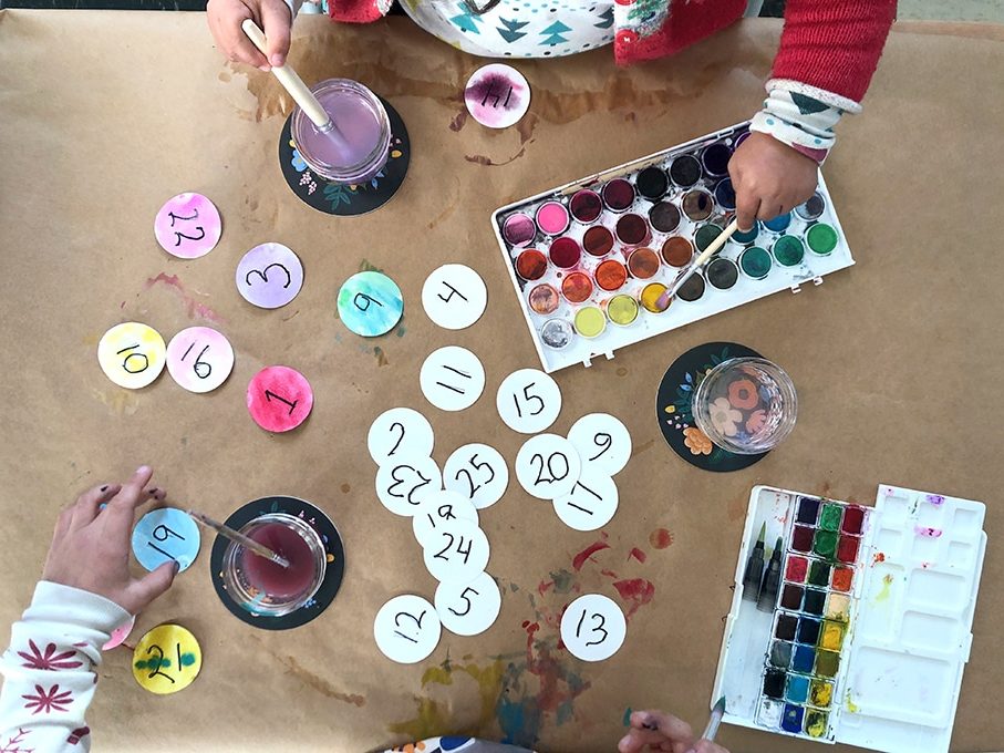 Kids painting paper ornaments with watercolors