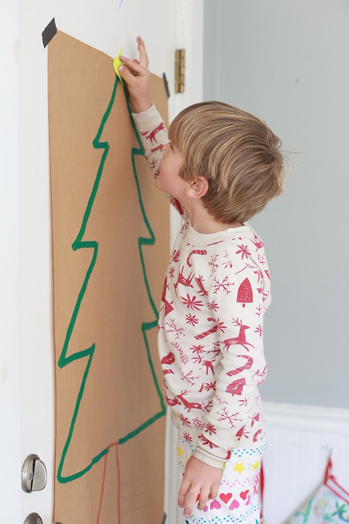child adding star to paper tree