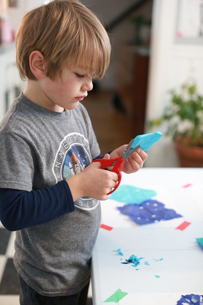 Child cutting paper snowflakes with tissue paper