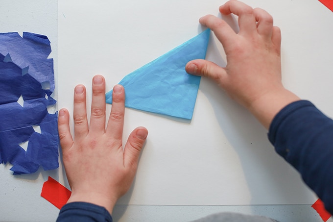 Child folding tissue paper snowflakes