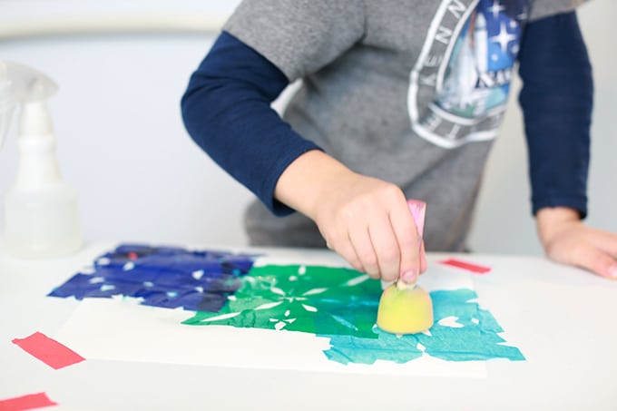 Child tapping wet tissue paper to make print