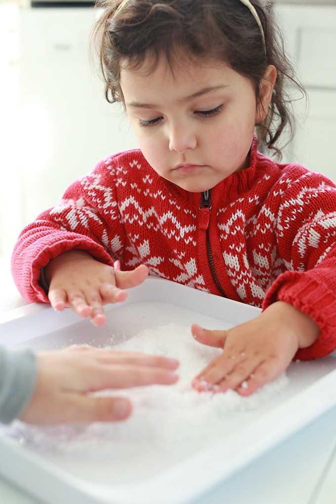 Child touching instant snow on tray