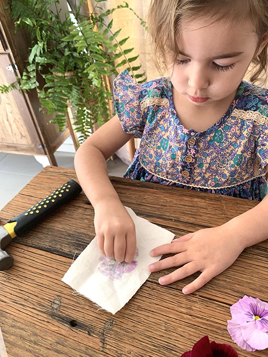 Child peeling off flower from canvas to create flower flags