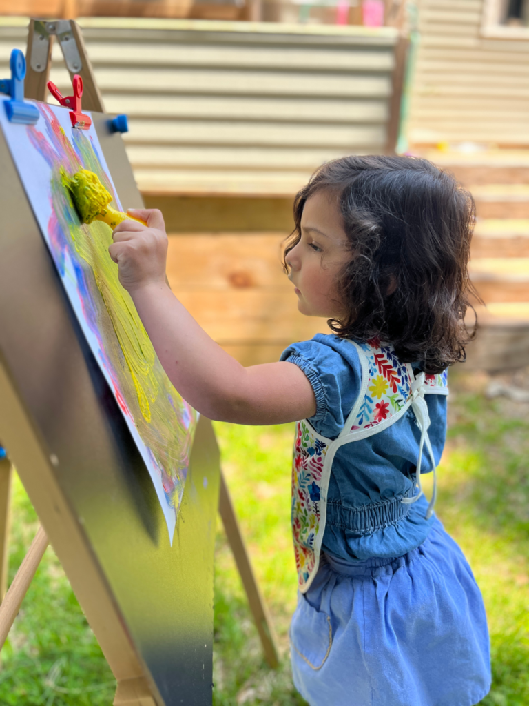 Ella painting at an easel
