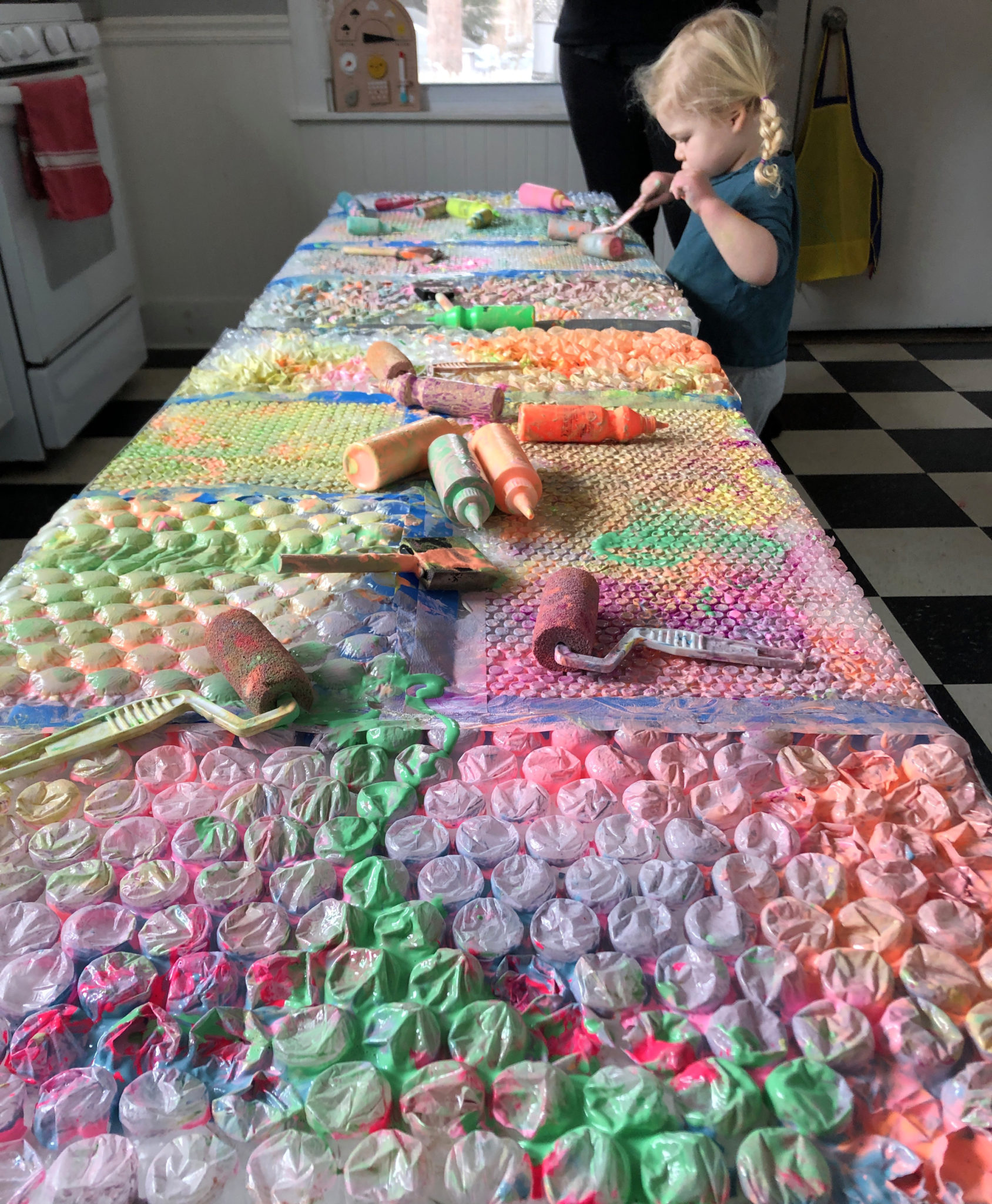 Child painting with bubble wrap at art table