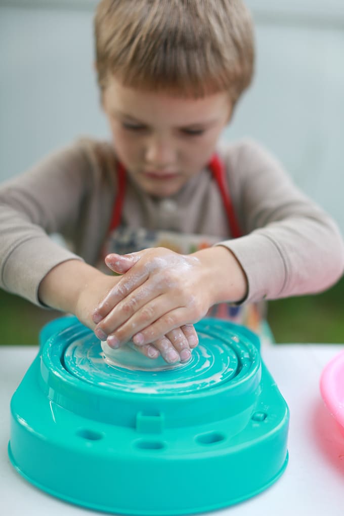child centering clay ball on kids pottery wheel