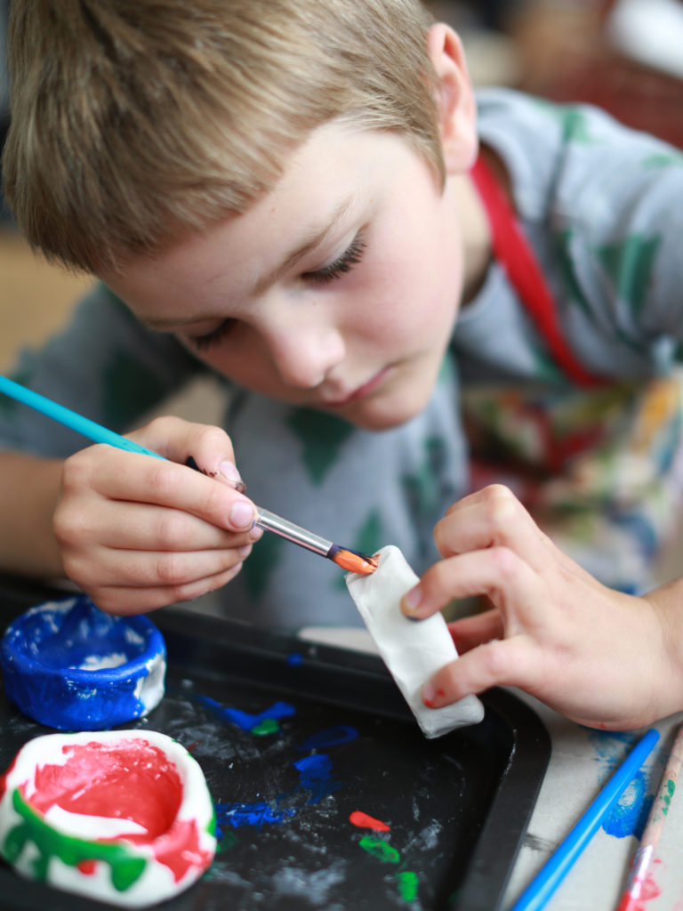 child painting clay pots