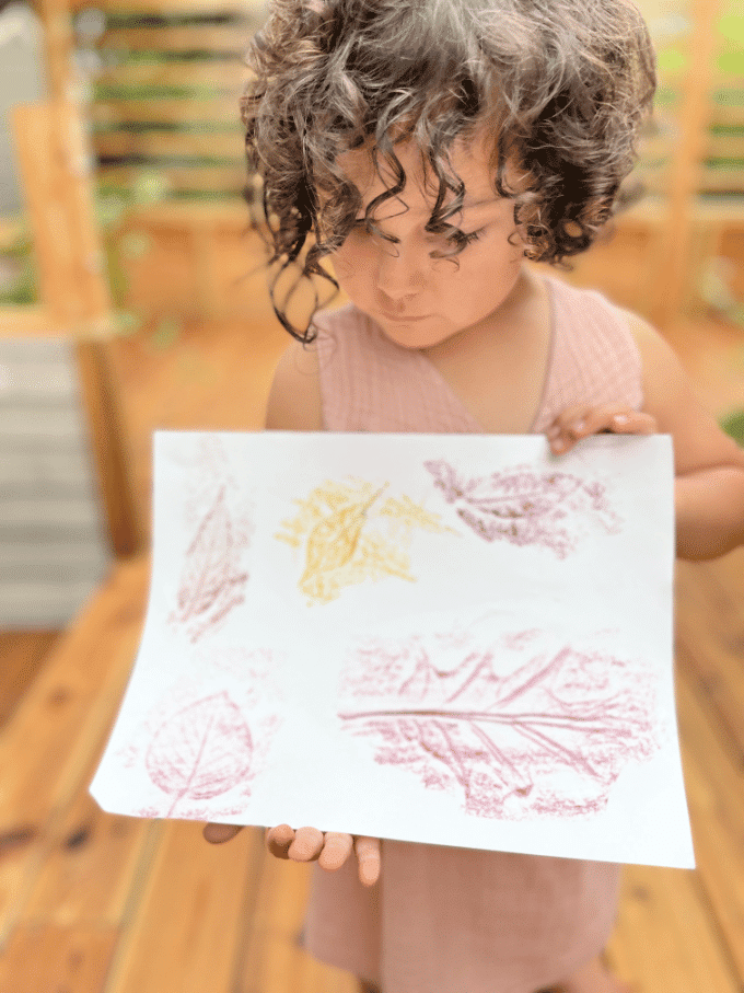 child with leaf rubbings