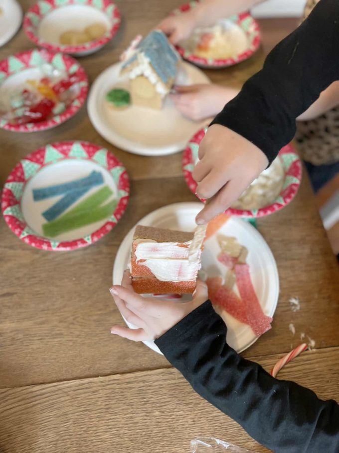 child adding icing to gingerbread house