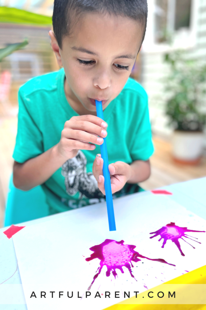child blowing paint with straws_pin