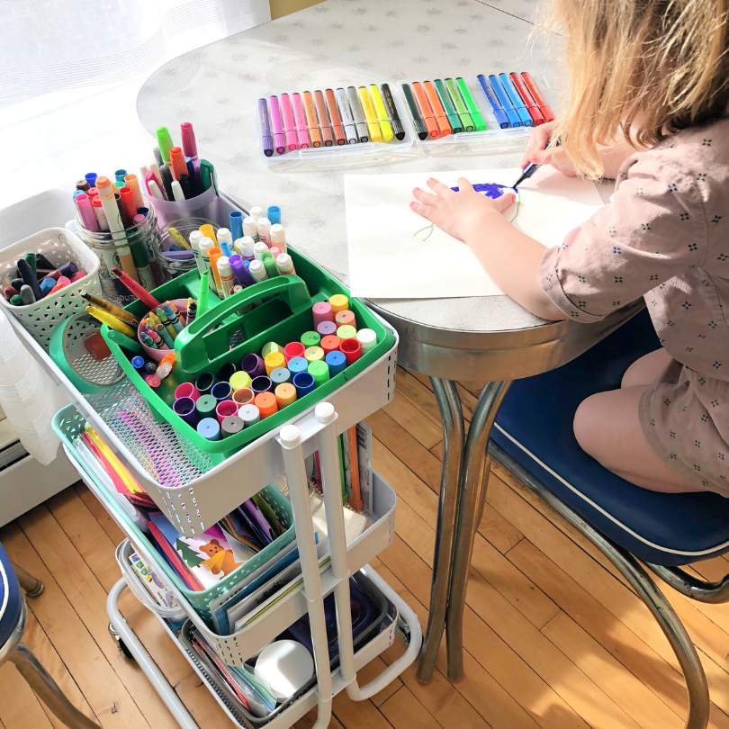 painting child sitting near art cart