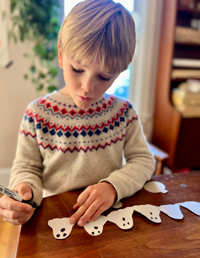 child drawing ghost faces for halloween garland