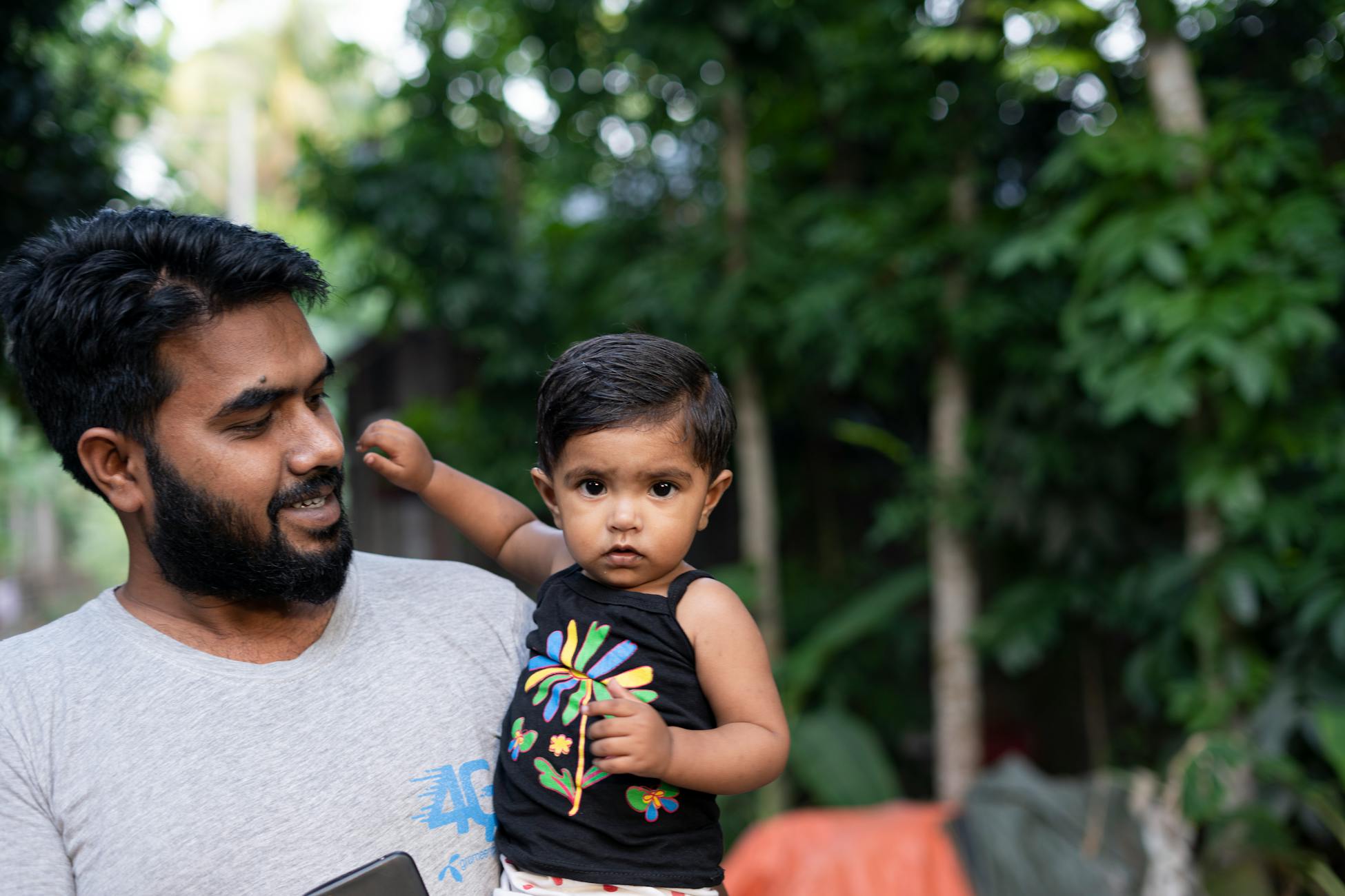 A father and child enjoying a bonding moment outdoors, surrounded by nature in Bangladesh.