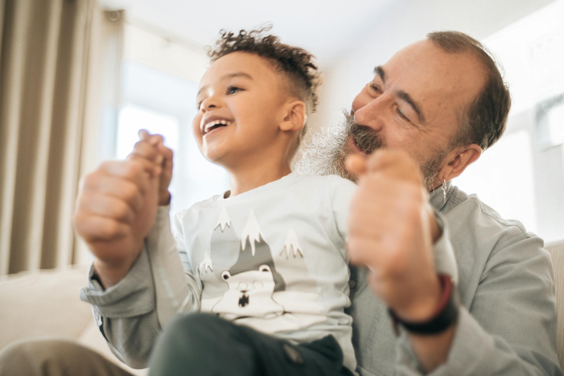 Happy moment of a grandfather and grandson enjoying time together indoors. Smiling and connected.
