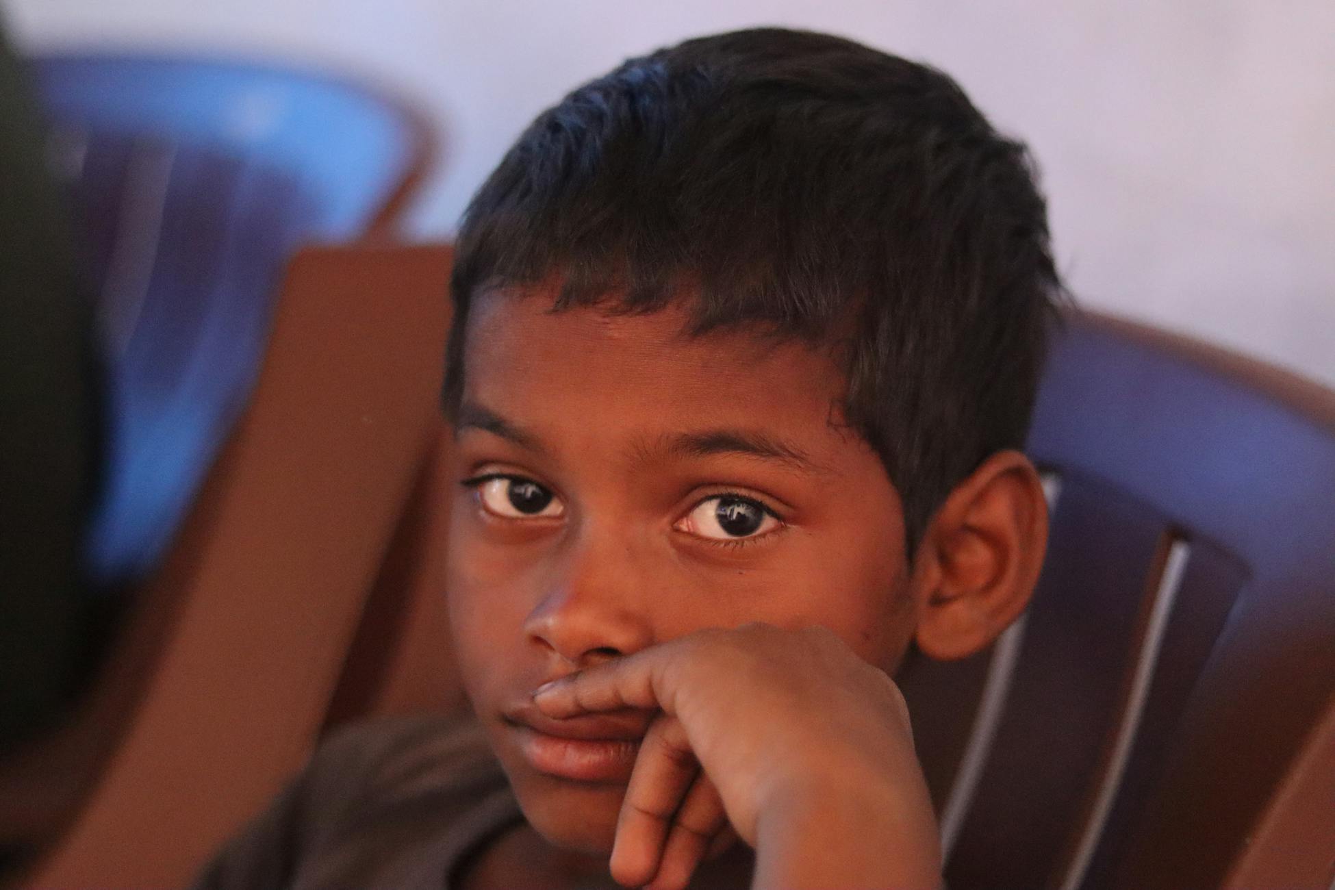 A close-up portrait of a thoughtful child resting chin on hand, deep in contemplation.