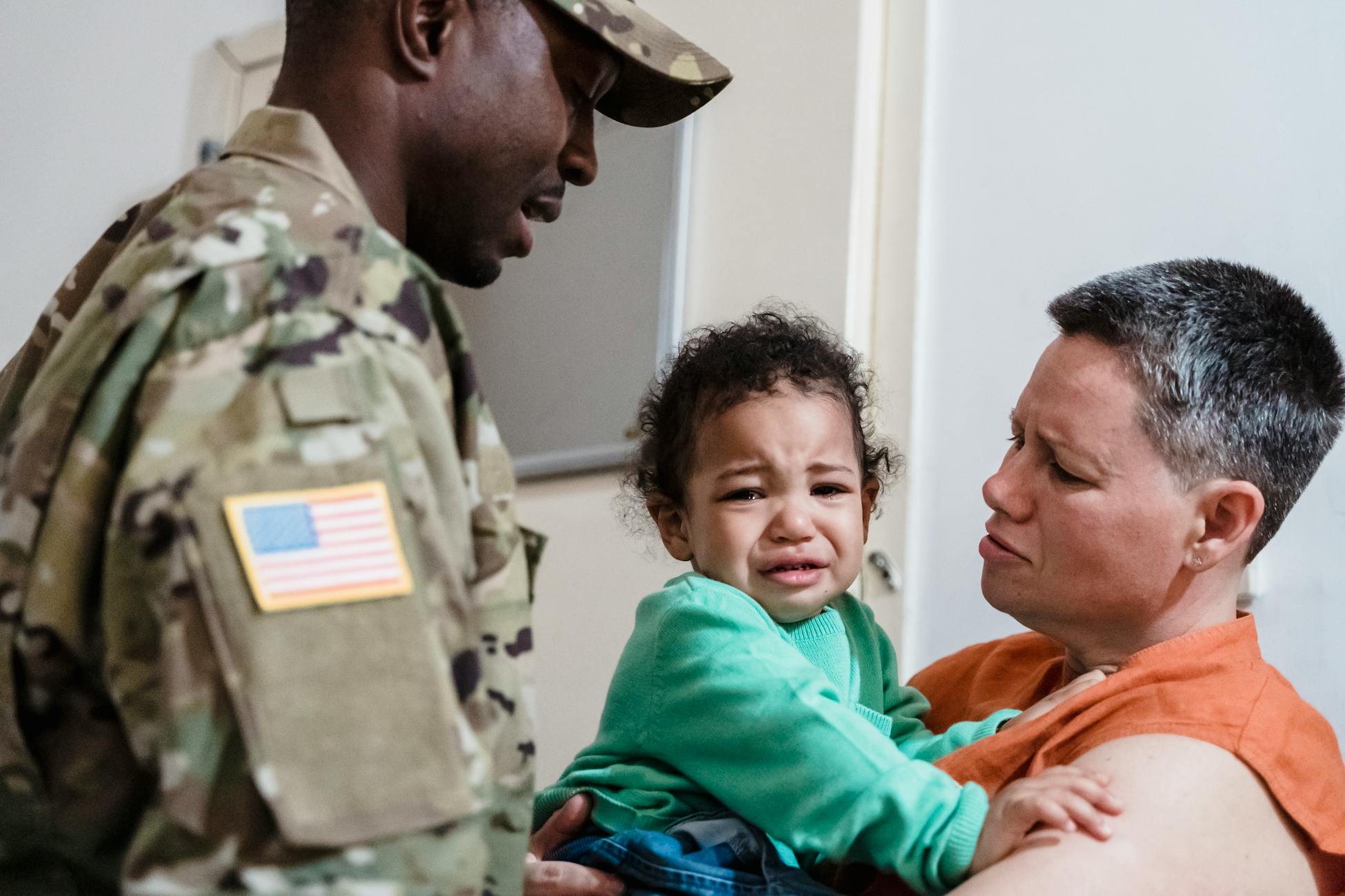 A family reunion depicting a soldier, mother, and crying child, showcasing strong emotions.