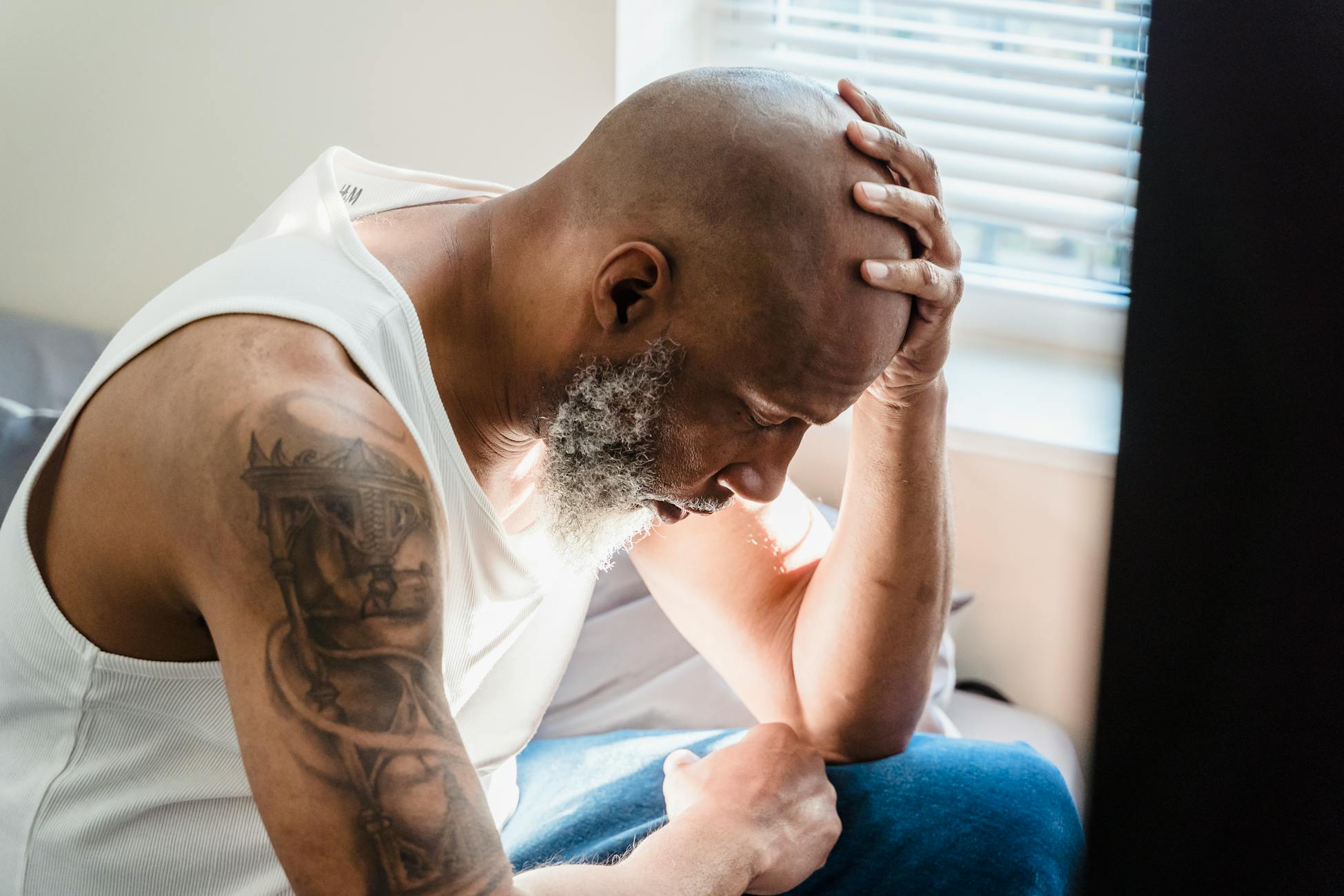 A senior man sits thoughtfully at home, conveying emotions of contemplation and stress.