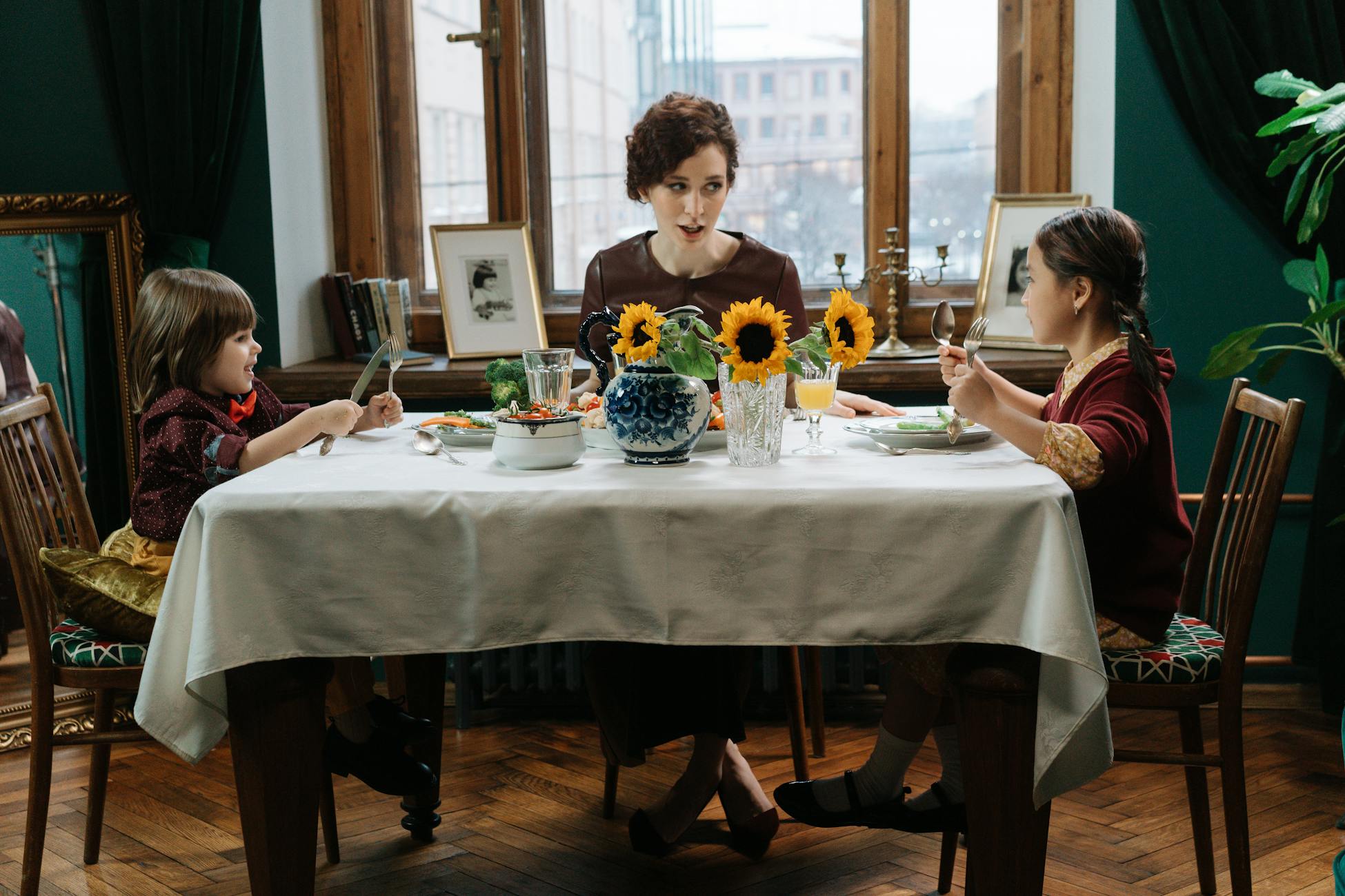A family enjoys a meal together with sunflowers on the table, capturing a warm and inviting dining scene.