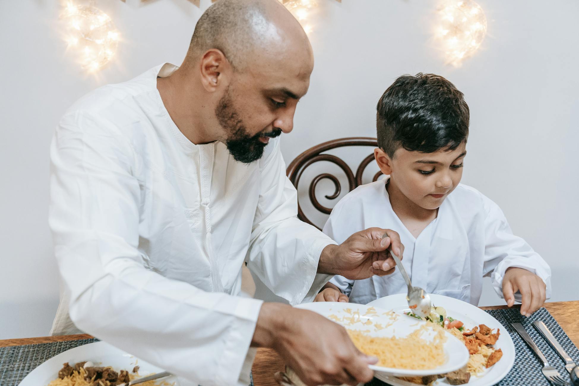 Father and son enjoying a home-cooked meal together indoors, sharing quality family time.