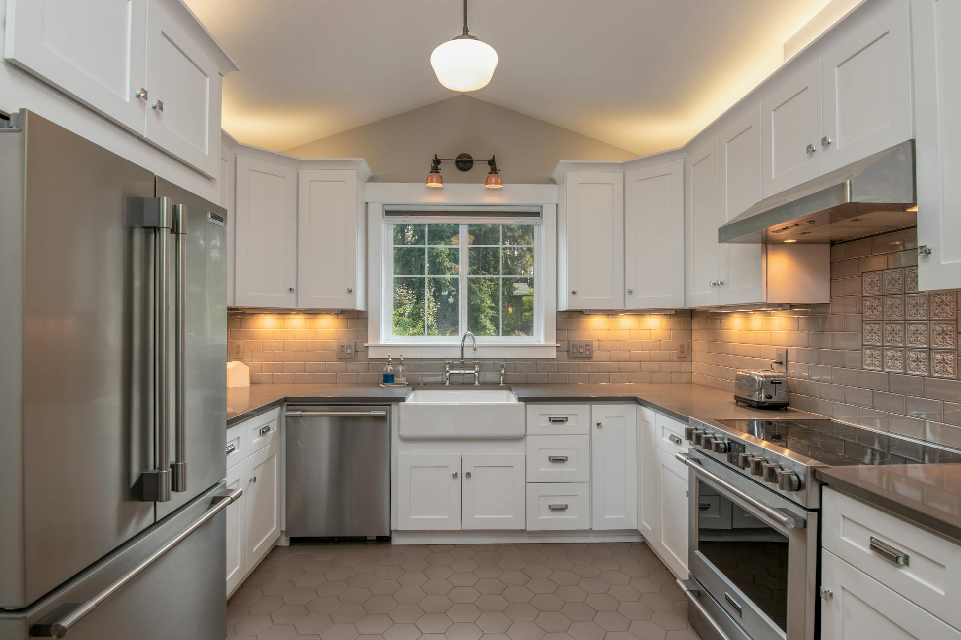 A bright and modern kitchen featuring sleek white cabinets and stainless steel appliances.