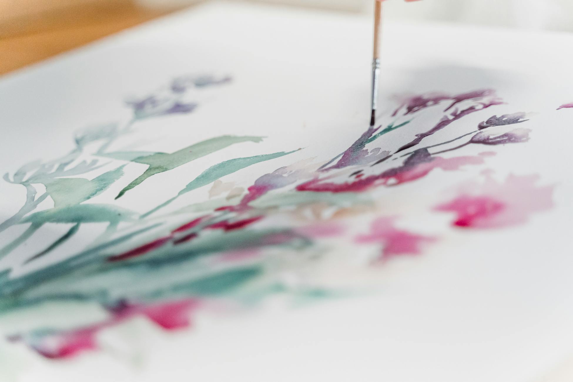 A soothing watercolor painting of delicate flowers in progress, highlighting soft brushstrokes.