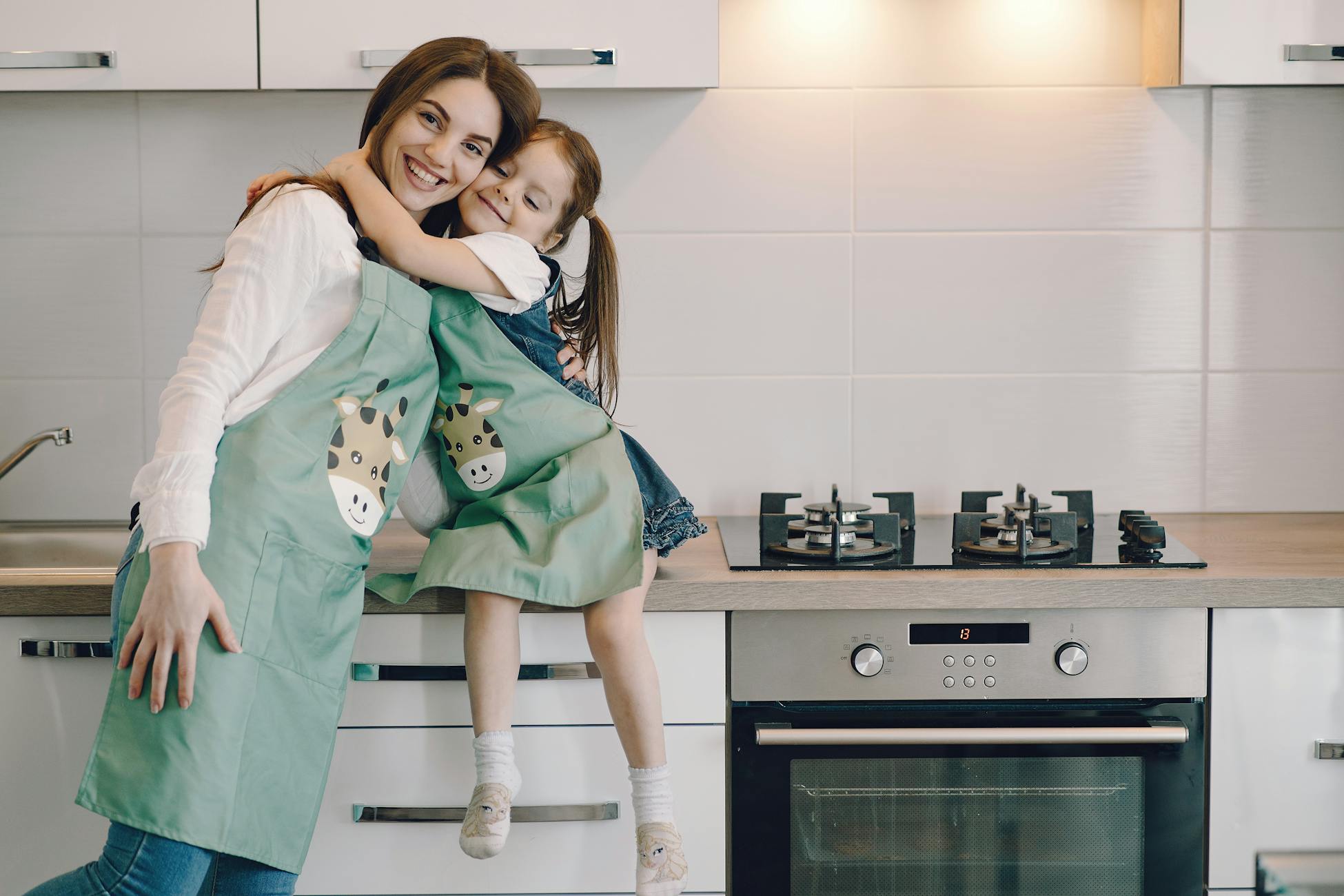 A joyful mother and daughter sharing an affectionate hug in a contemporary kitchen setting.