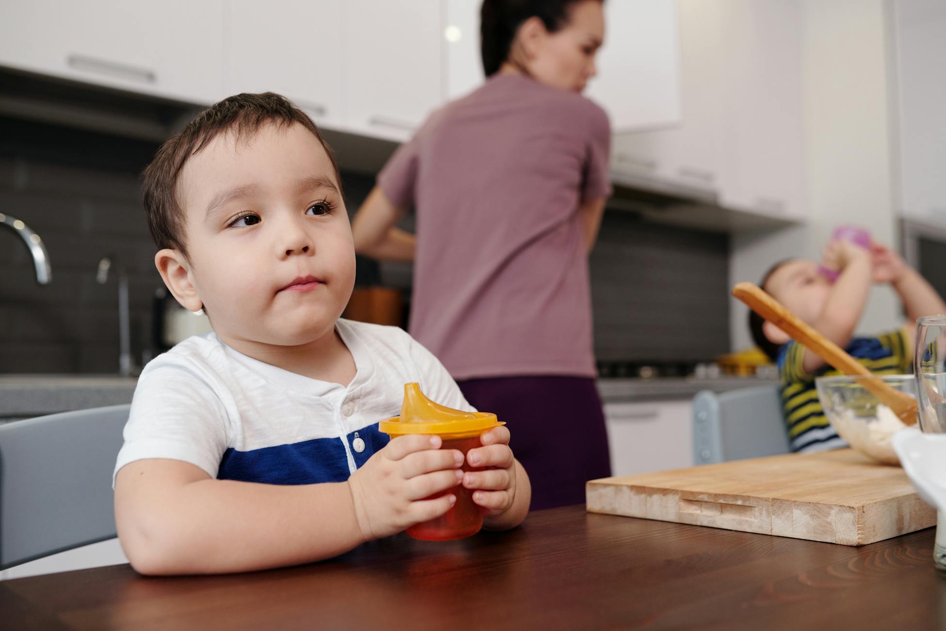 Young children with a mother in a domestic kitchen setting, showcasing family time.