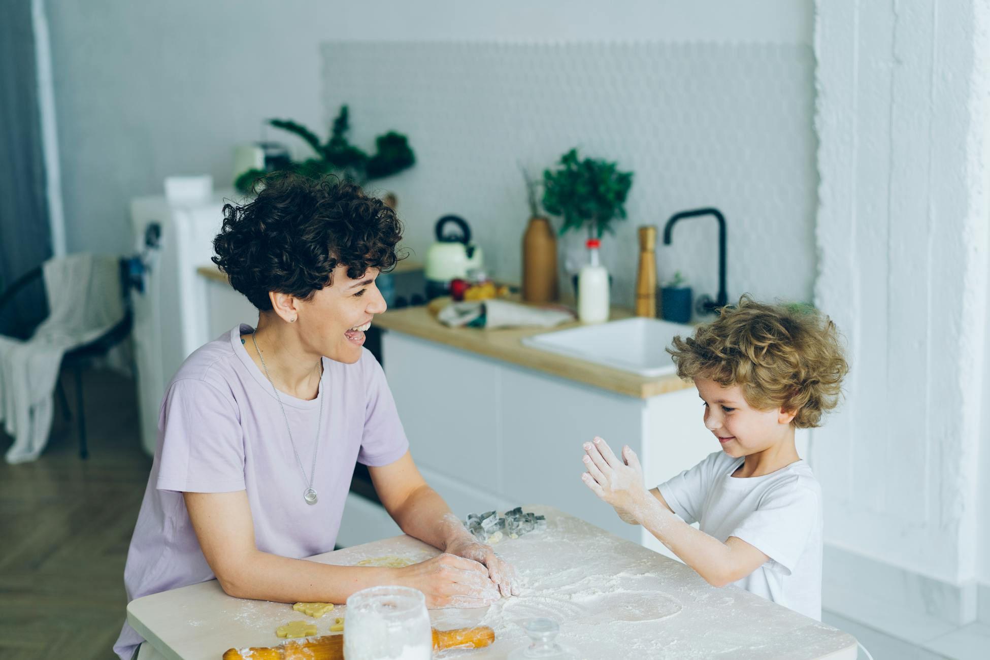 Joyful mother and son enjoying bonding and baking in a bright kitchen.