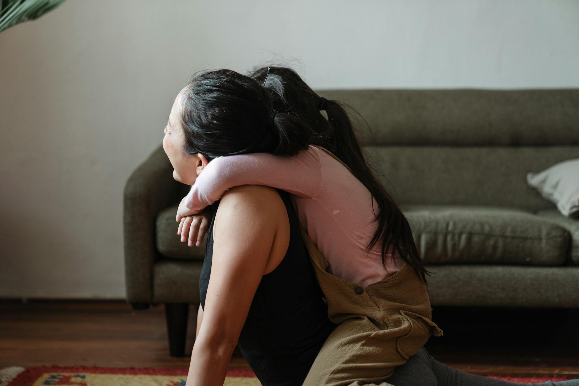 A loving embrace between mother and daughter in a cozy living room setting.
