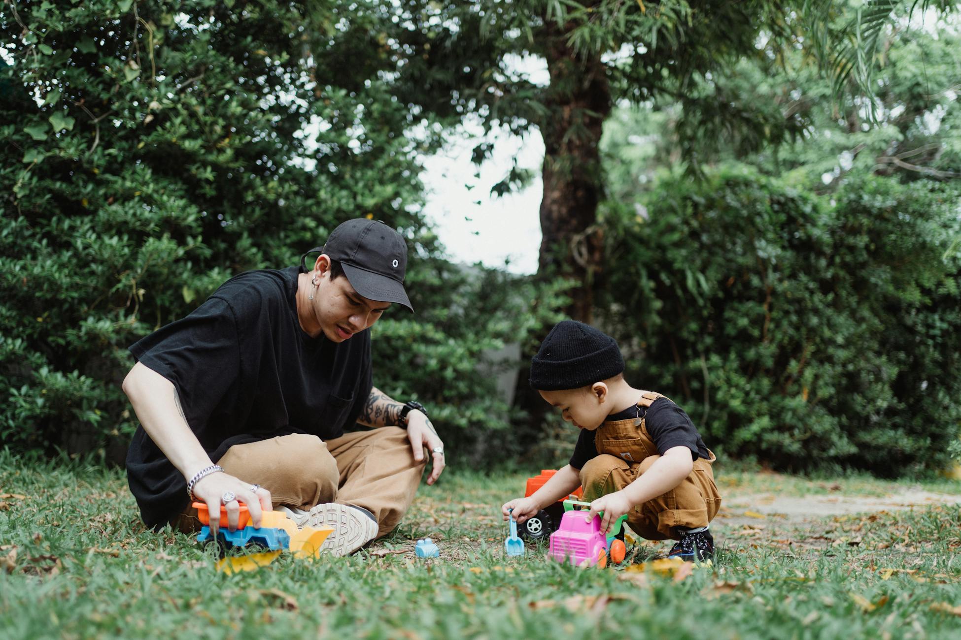 A father and son enjoy quality playtime outdoors with toy cars, bonding in nature.