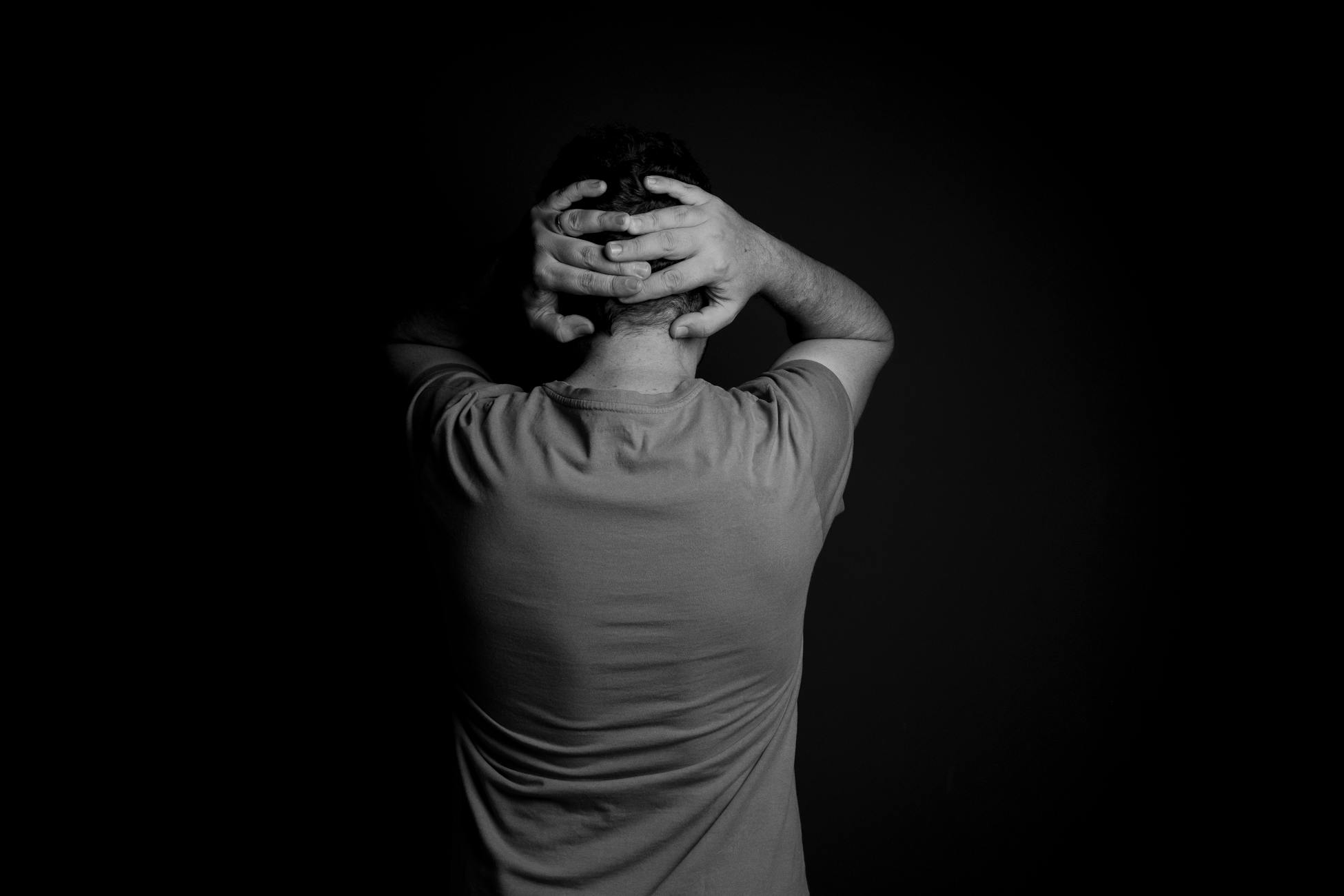 Black and white portrait of a man with hands on head, conveying stress and frustration.
