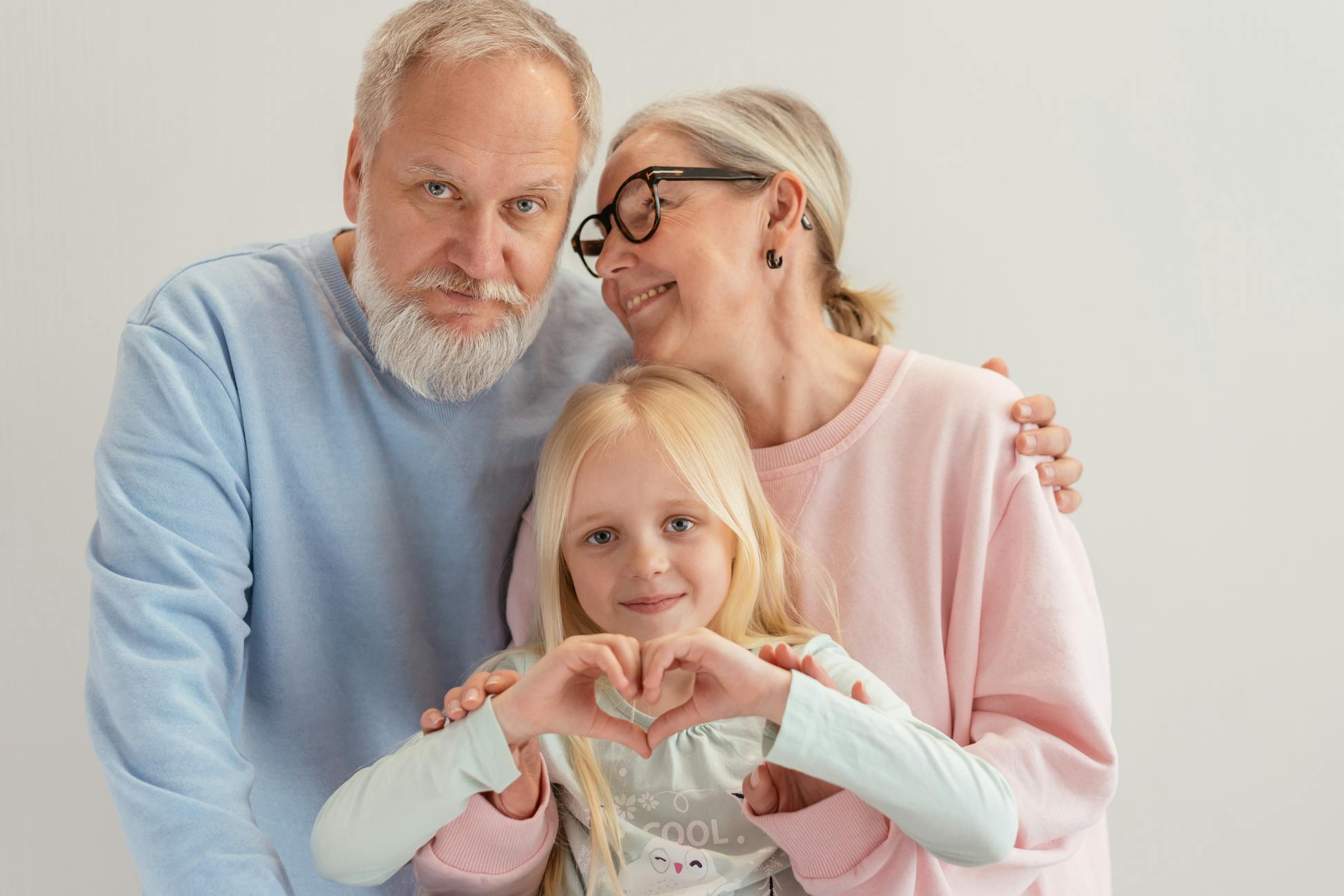 A warm and affectionate family portrait of grandparents embracing their granddaughter indoors.