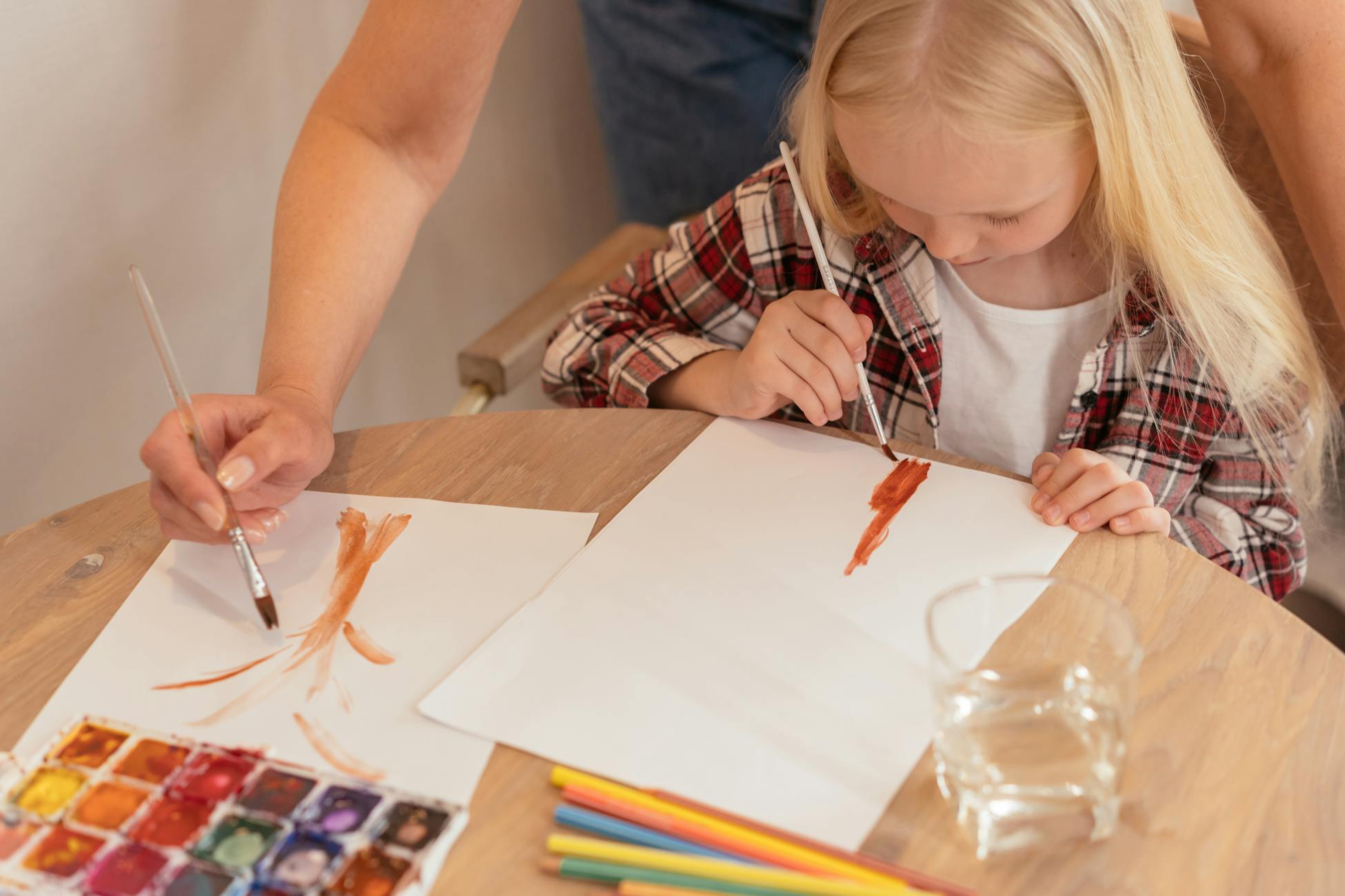 Young girl painting with watercolors, highlighting creativity indoors.