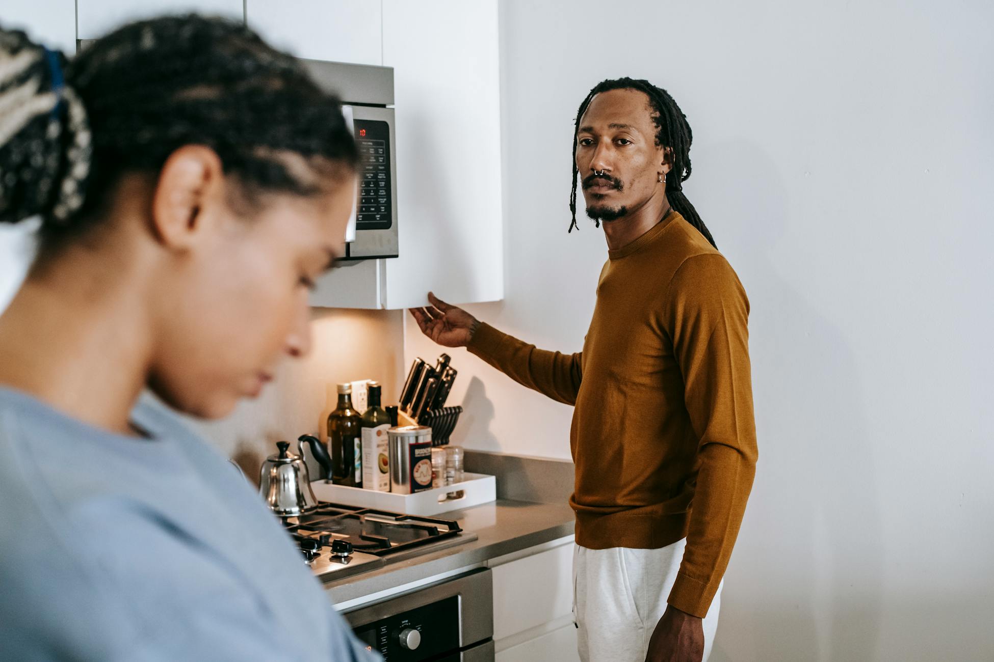Young black couple in casual outfit standing at kitchen and arguing with each other at home