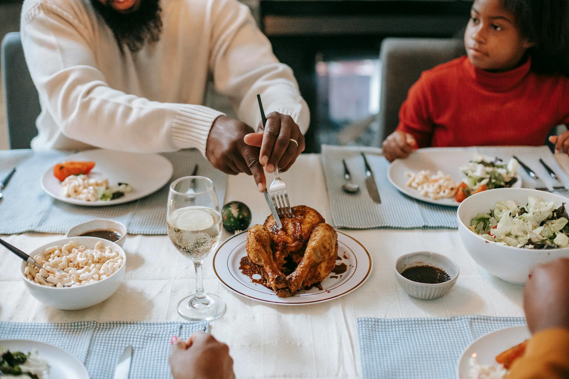 A cozy family dinner featuring roast chicken, salads, and macaroni on a beautifully set table.