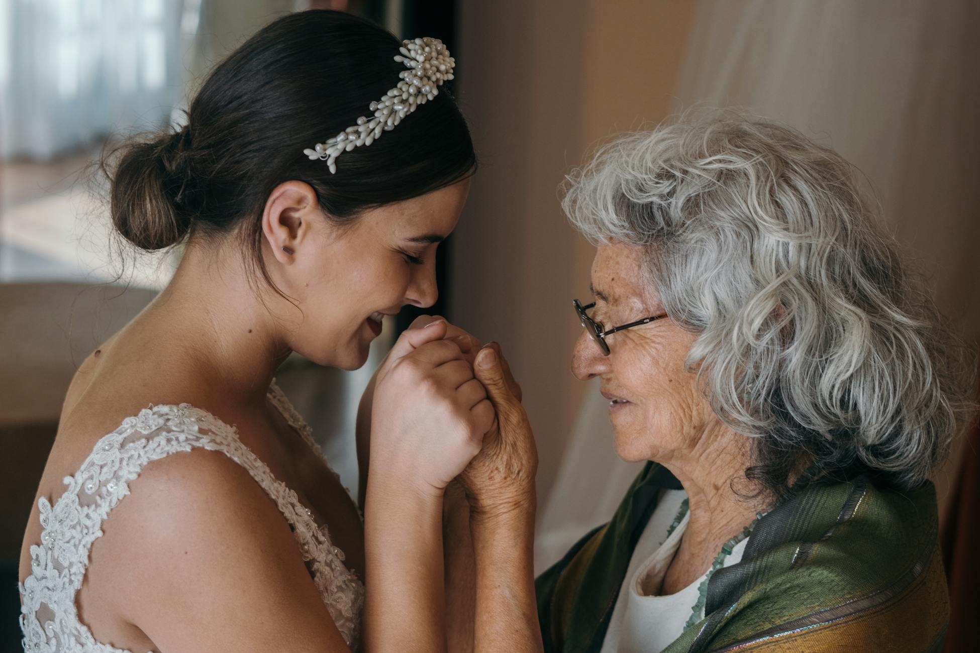 A bride and elderly woman share a tender embrace on a wedding day, symbolizing love across generations.