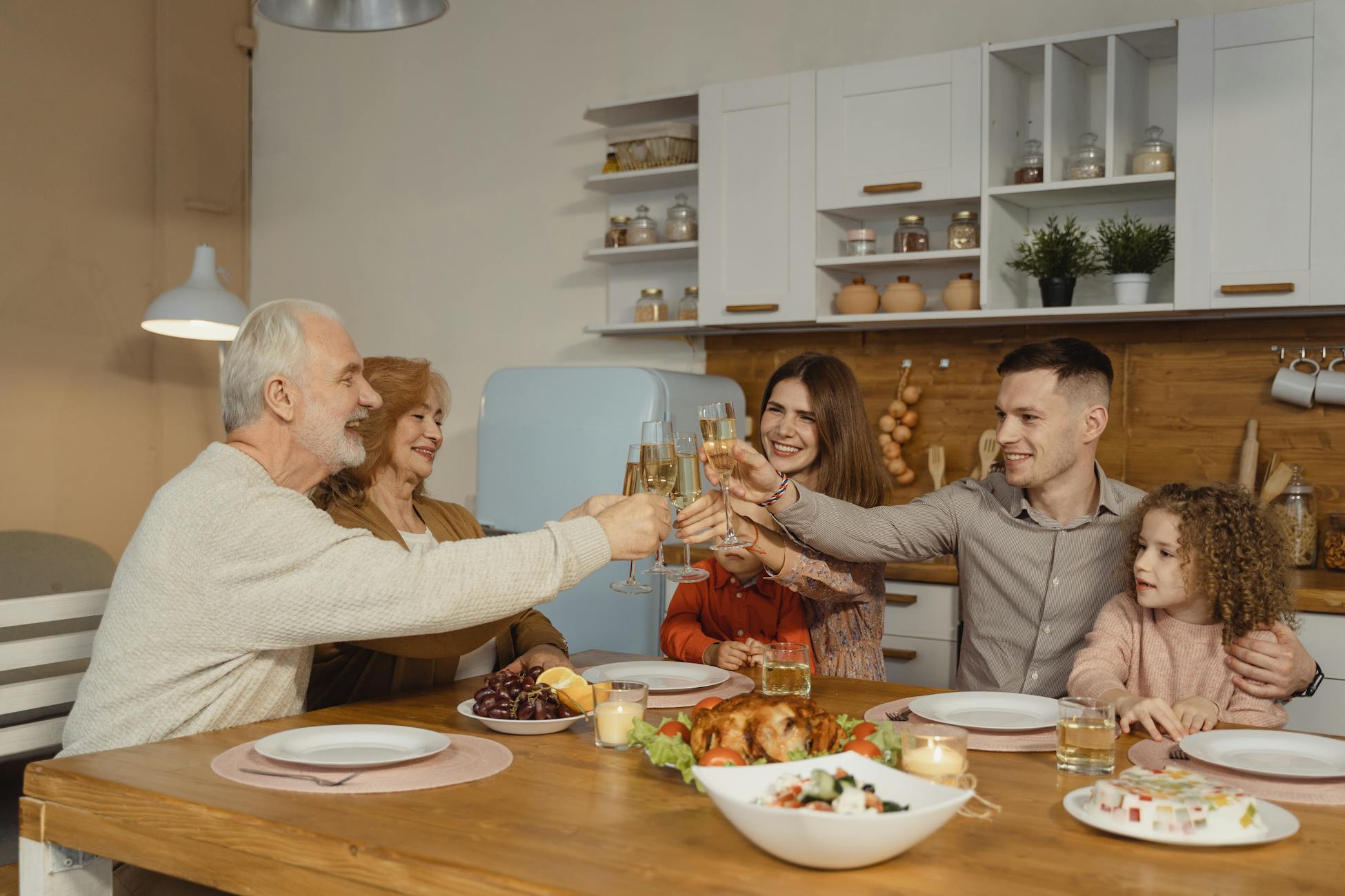 A joyful family toasting at a dinner table indoors, celebrating a special occasion.