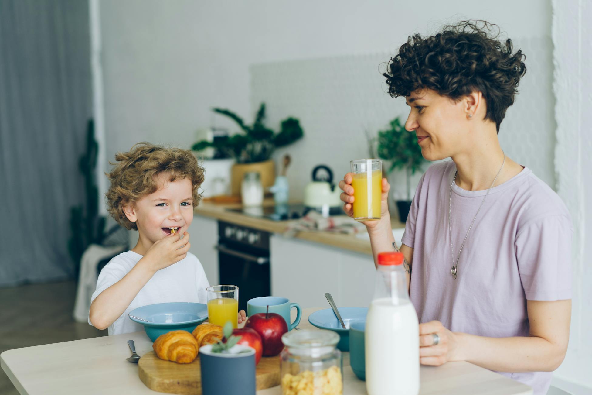 Mother and son sharing a joyful breakfast at home. Smiling and bonding over food and drinks.