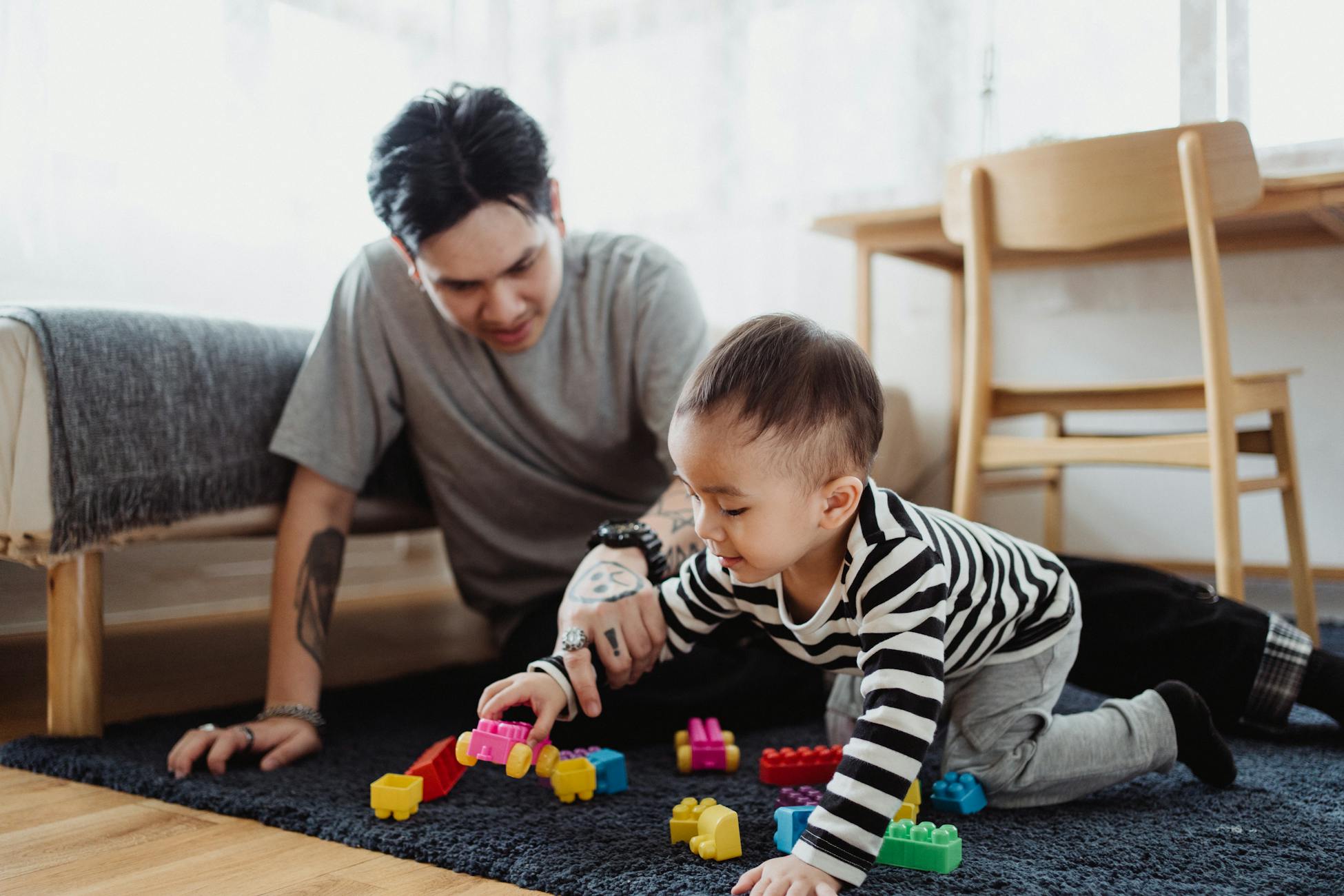 Father bonding with son while playing with colorful blocks in a cozy home setting.