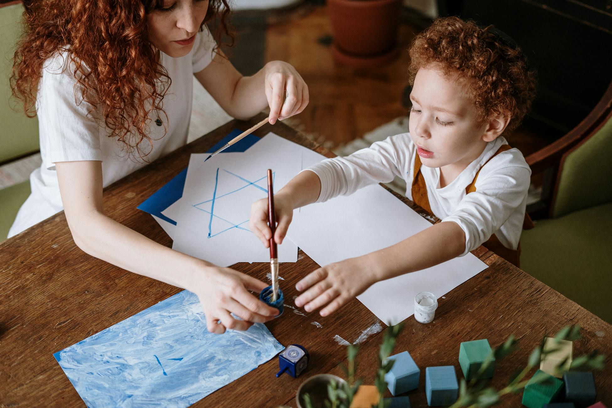 A mother and child engage in a fun and creative art session indoors focusing on painting and drawing.