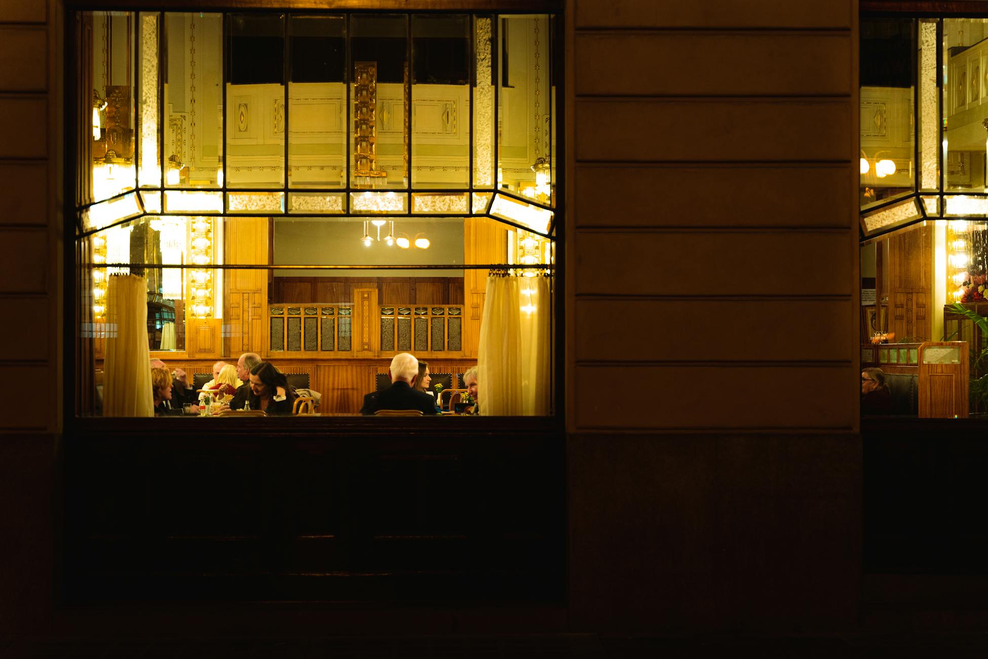 A warm and inviting view of an elegant restaurant interior in Prague, showcasing diners enjoying a peaceful evening meal.