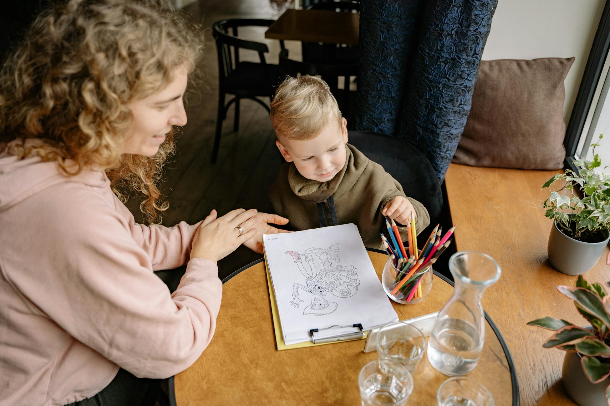 A mother and son drawing together at a table, fostering creativity and bonding.