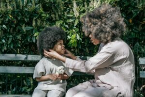 A touching scene of a mother and child bonding in a lush green park setting.