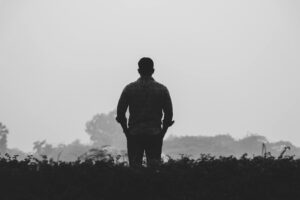 Silhouette of a man standing outdoors in a foggy, tranquil landscape.