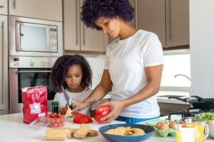 A mother and daughter cooking together, preparing a healthy meal in a modern kitchen.